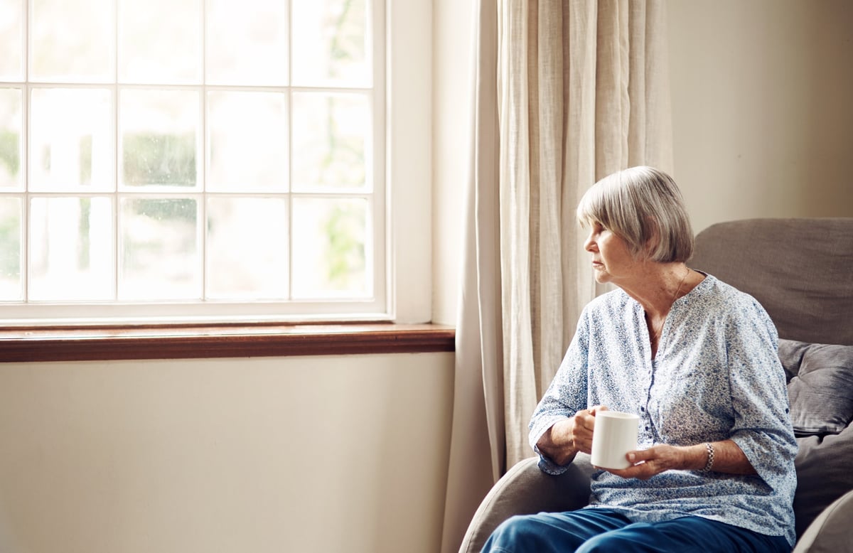 Shot of a senior woman having coffee and looking thoughtfully out of a window