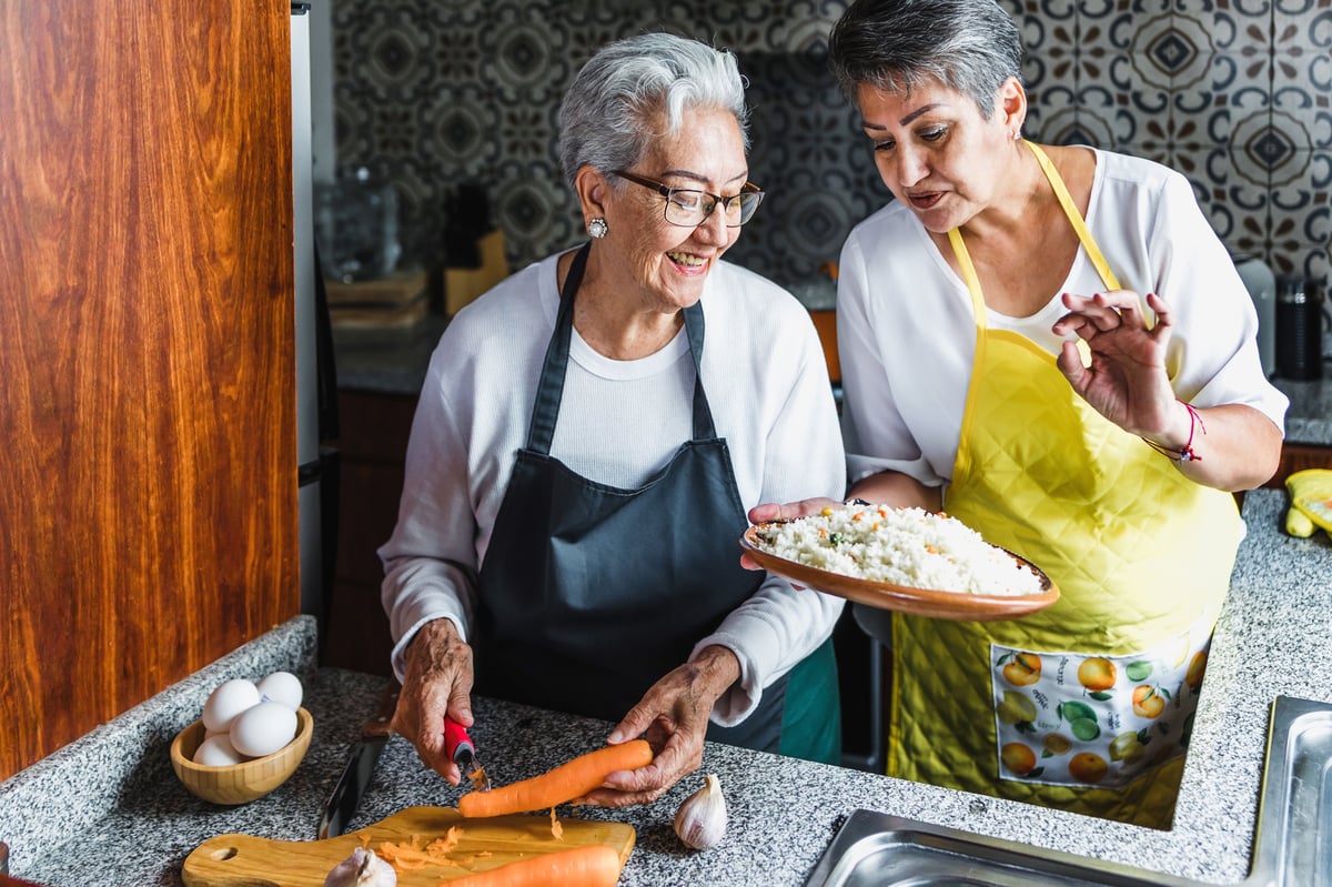 Hispanic women grandmother and daughter cooking at home kitchen