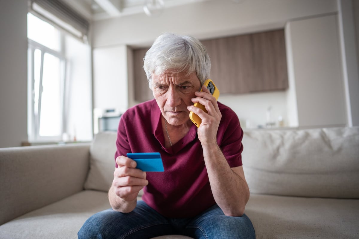 Naive elderly pensioner trusting sharing card number with scammers on phone — phone scam, identity theft and financial deception