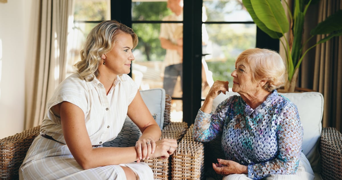 An elderly mother and her adult daughter having a supportive conversation at home, sharing memory and connection