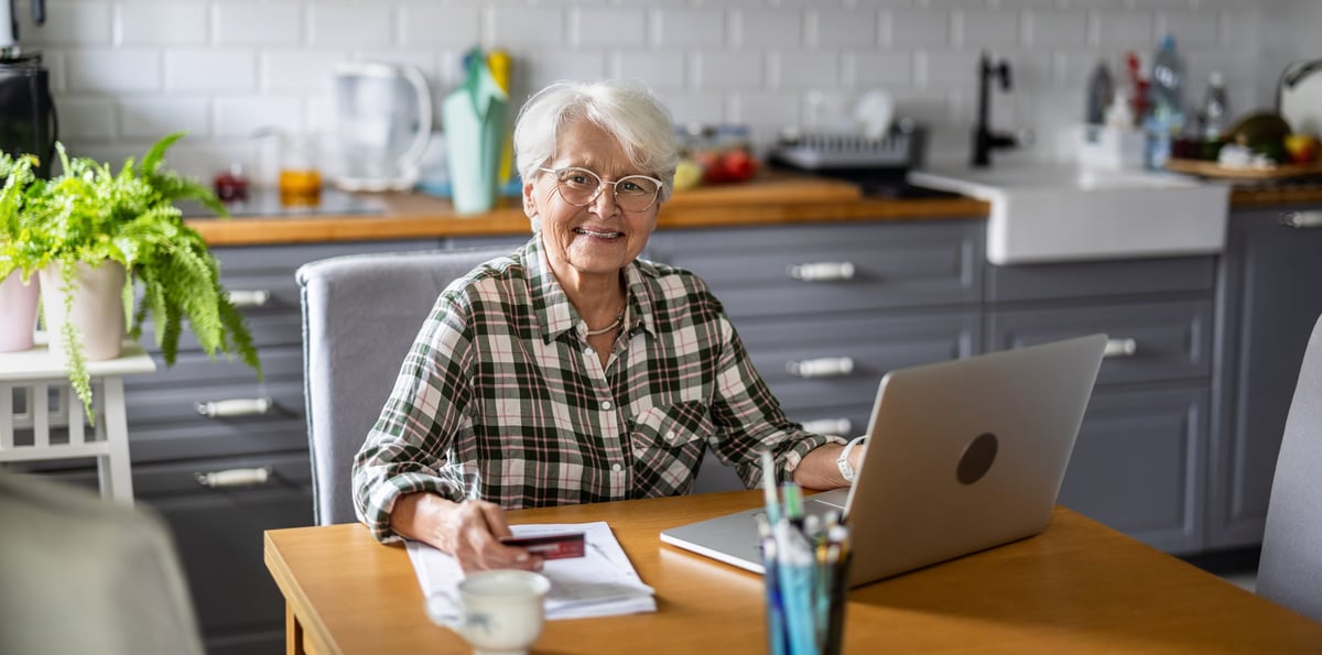 Senior woman using laptop and credit card for online shopping at home