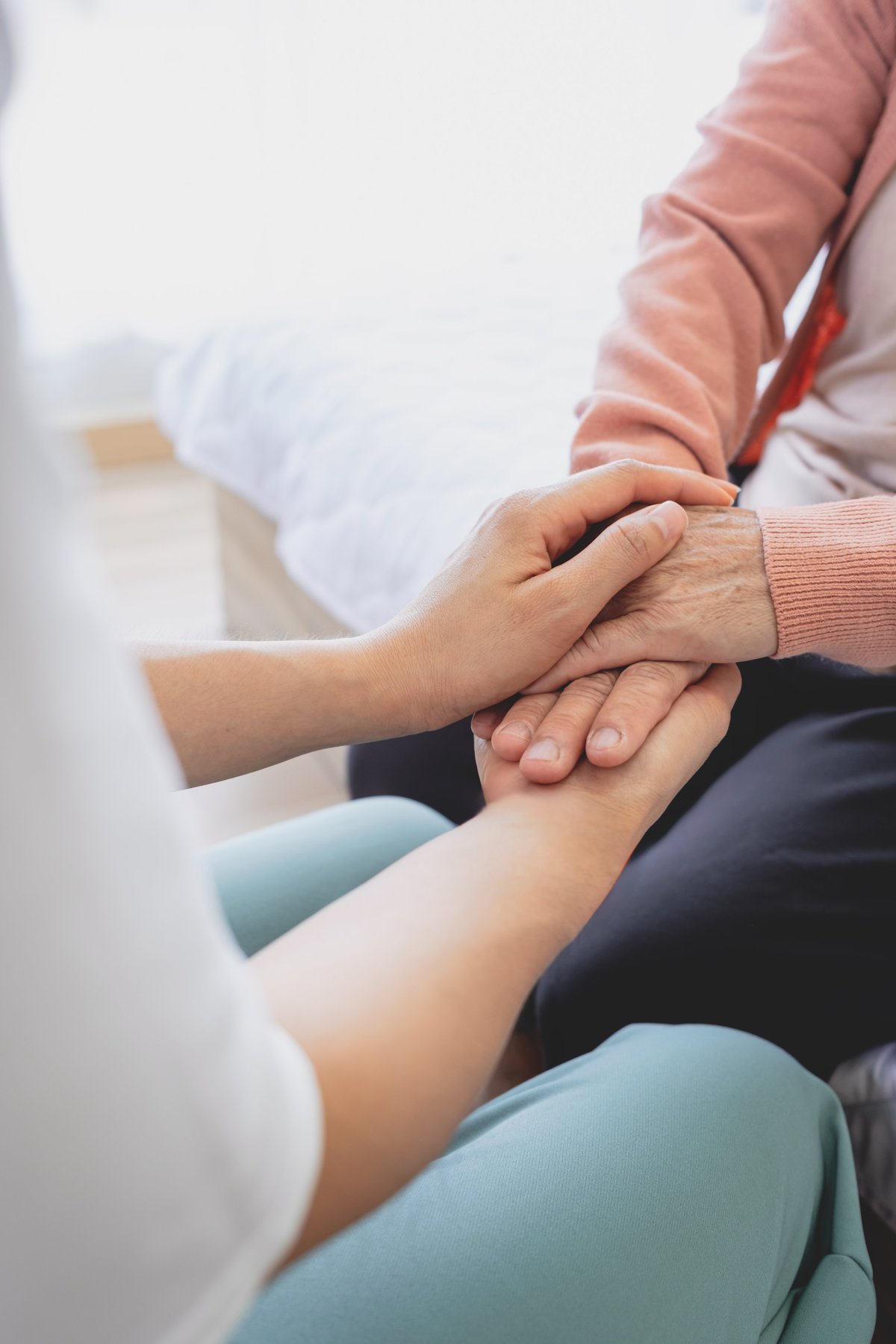 A woman holds hands and gives love to her elderly mother at home, creating bonding and happiness. love and care concept