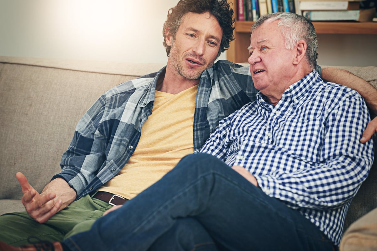 Shot of a mature man and his elderly father sitting on the sofa at home and having a chat